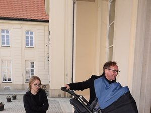 Andrzej Chyra z synkiem w niebieskim wózku i partnerką Pauliną przed ministerstwem kultury