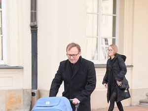 Andrzej Chyra w czarnym płaszczu z synkiem w niebieskim wózku i partnerką Pauliną przed ministerstwem