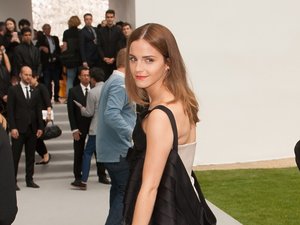 Emma Watson patrzy przez ramię w obiektyw, zdjęcie całej sylwetki