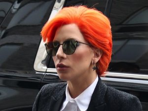 Lady Gaga w pomarańczowych włosach, ciemnych okularach i czarnym garniturze