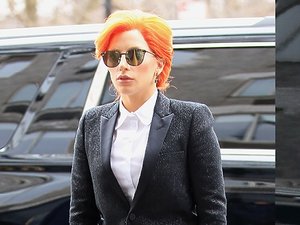Lady Gaga w rudych włosach, białej koszuli, czarnej marynarce i okularach