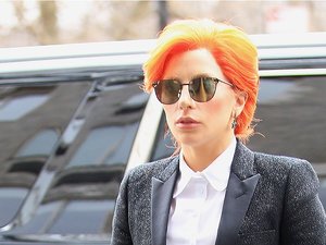 Lady Gaga w rudych włosach, ciemnych okularach i czarnym garniturze