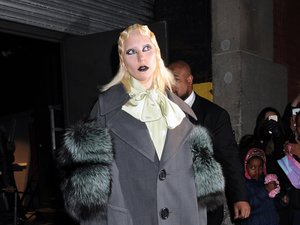 Lady Gaga w szarym płaszczu, białej bluzce z żabotem