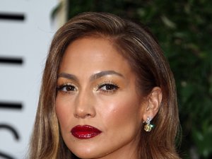 Jennifer Lopez w żóltej sukience, diamentowym naszyjniku i z czerwonymi ustami